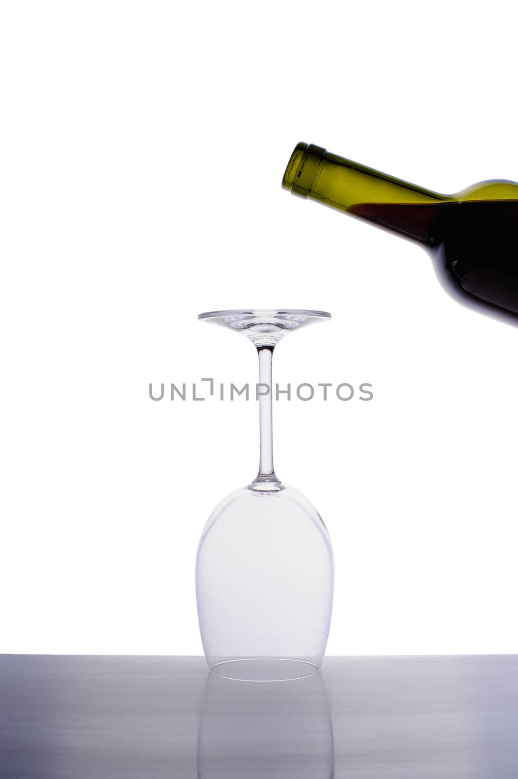 Inverted empty wine glass and bottle of red wine by nvelichko
