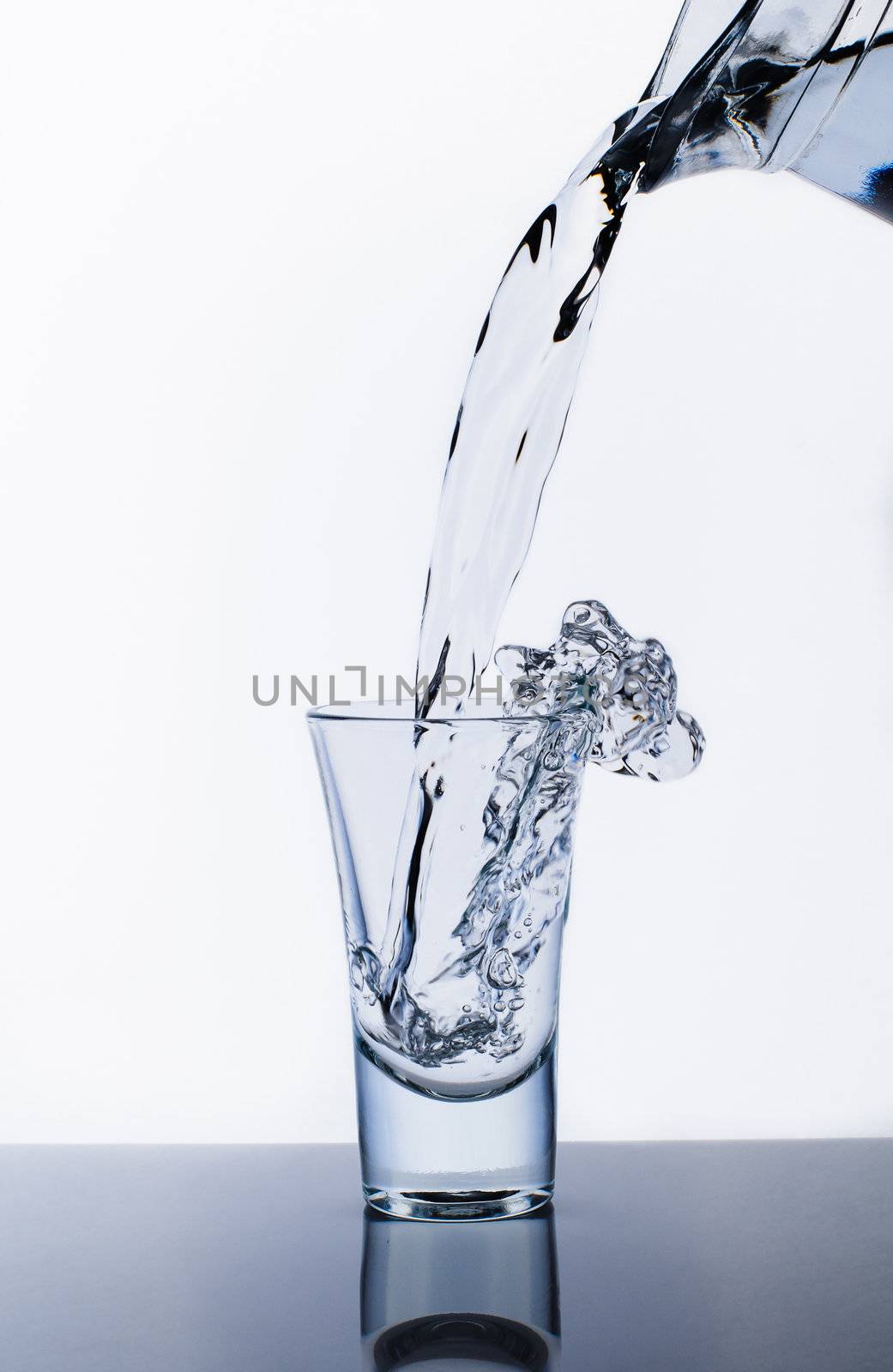 Decanter and glass with water splashes. Isolated on white background