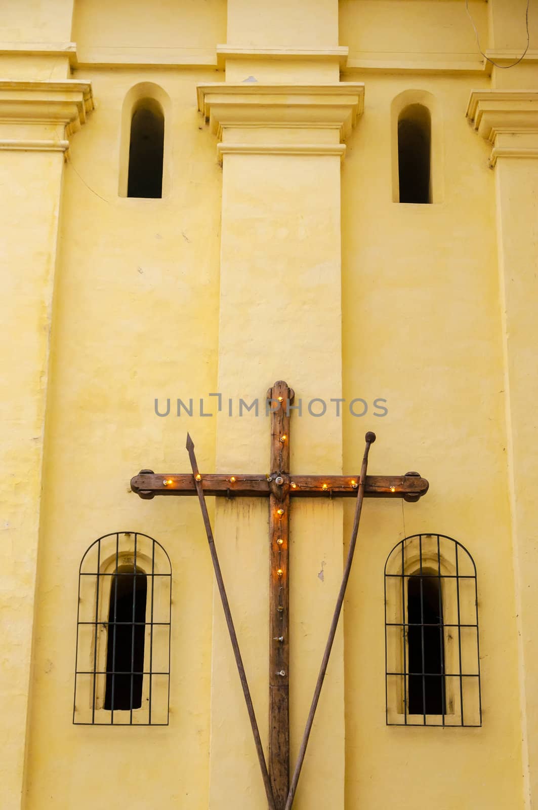 A yellow church with a wooden cross with lights in Popayan, Colombia