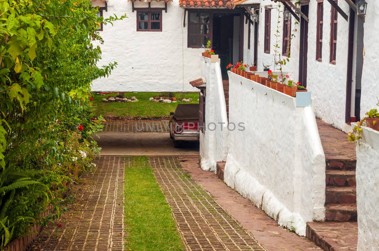 Old red classic car next to white colonial style houses