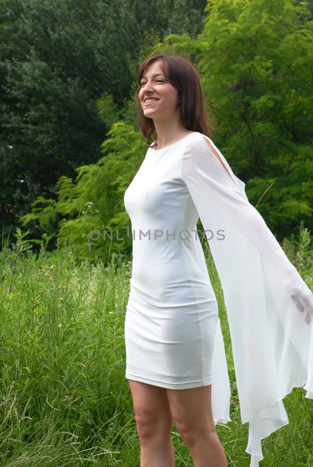 young happy caucasian brunette woman in white dress in green park outdoor