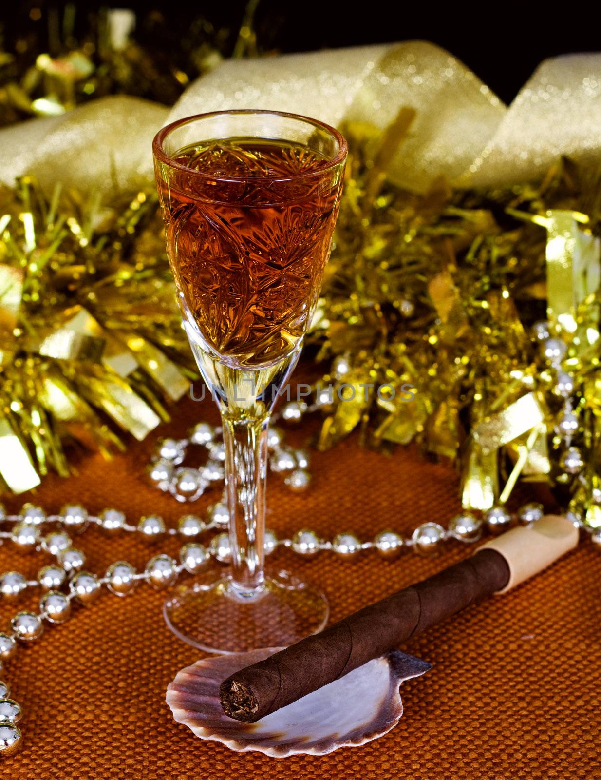Crystal glass with brandy, cigars and Christmas decorations on a black background
