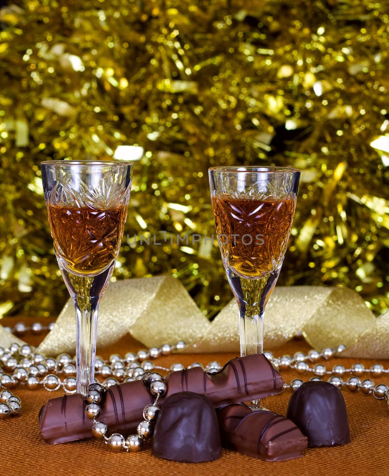 Crystal glasses of brandy and chocolate on the background of holiday lights
