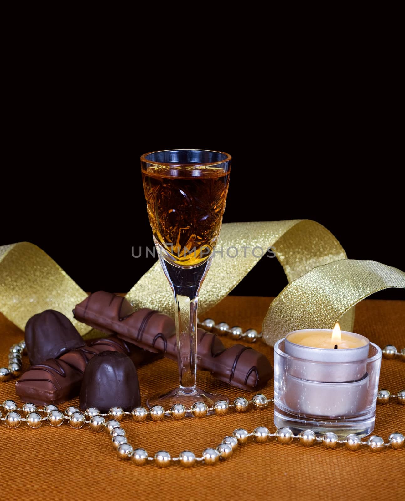 Crystal glass with cognac, chocolate and gold ribbon to mark the holiday.
