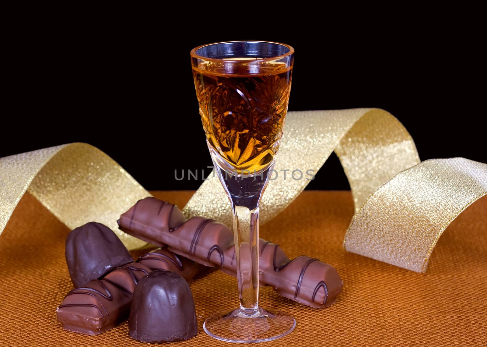 Crystal glass with cognac, chocolate and gold ribbon to mark the holiday
