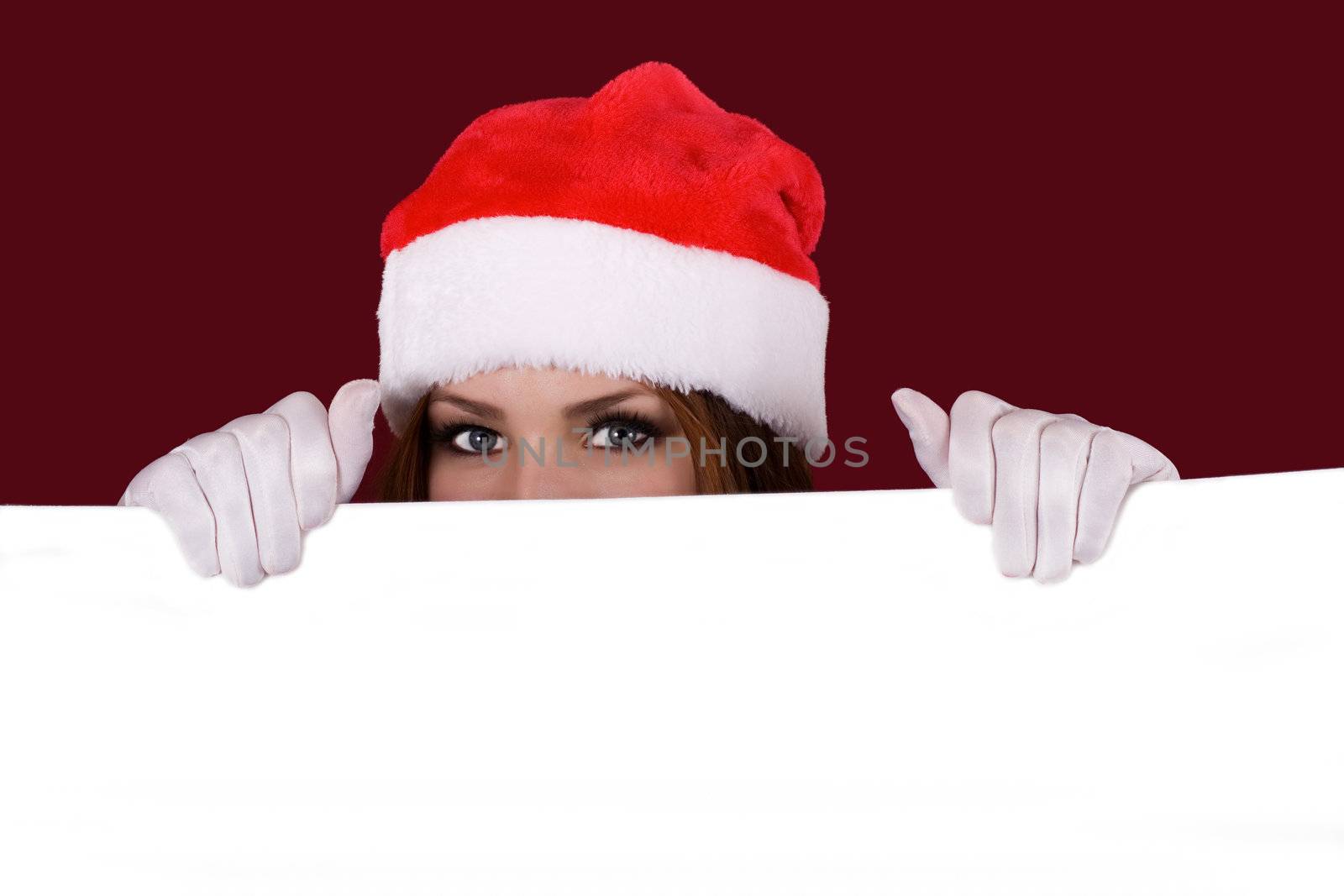 Portrait of happy girl with Christmas hat holding poster and pointing up