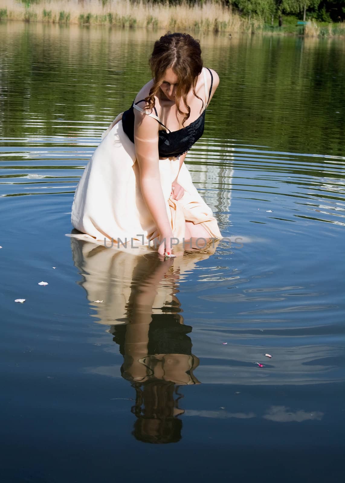 girl looks at his reflection in the water. The action takes place on the lake