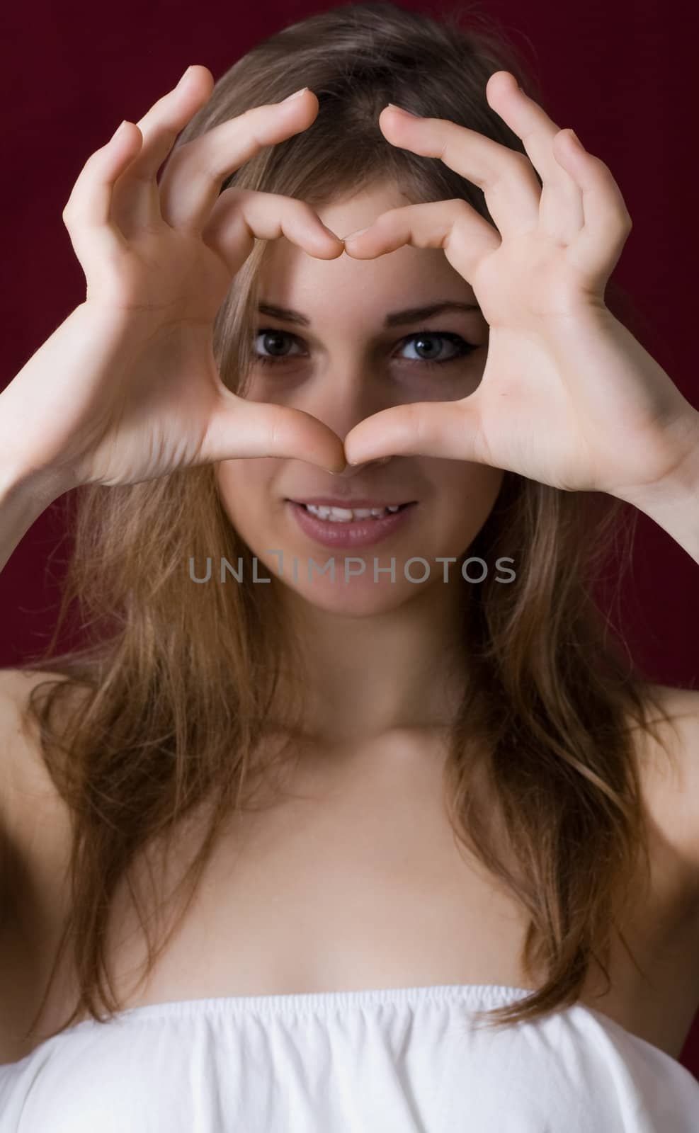Beautiful girl show love sign on a red background