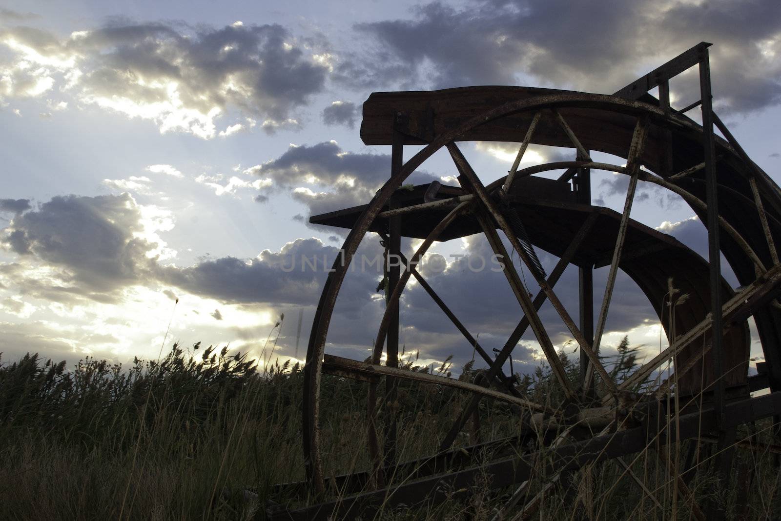 old farm equipment in field sunset by kjcimagery