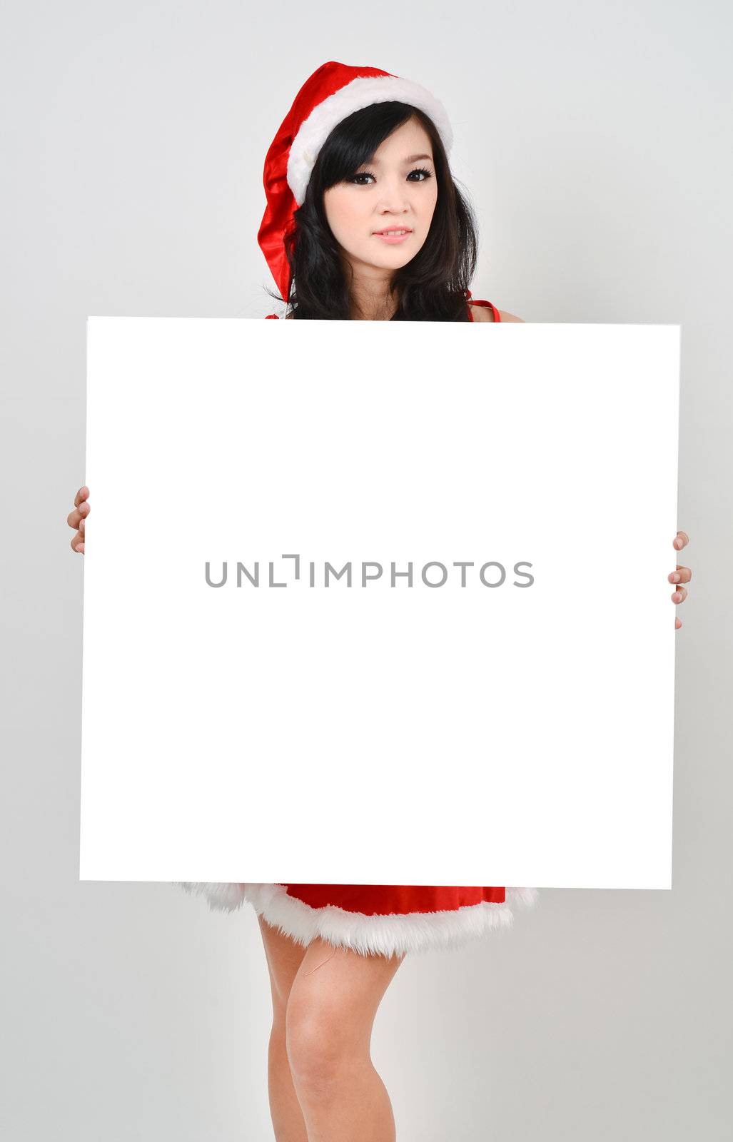 Santa woman  holding a white poster isolated a on gray background