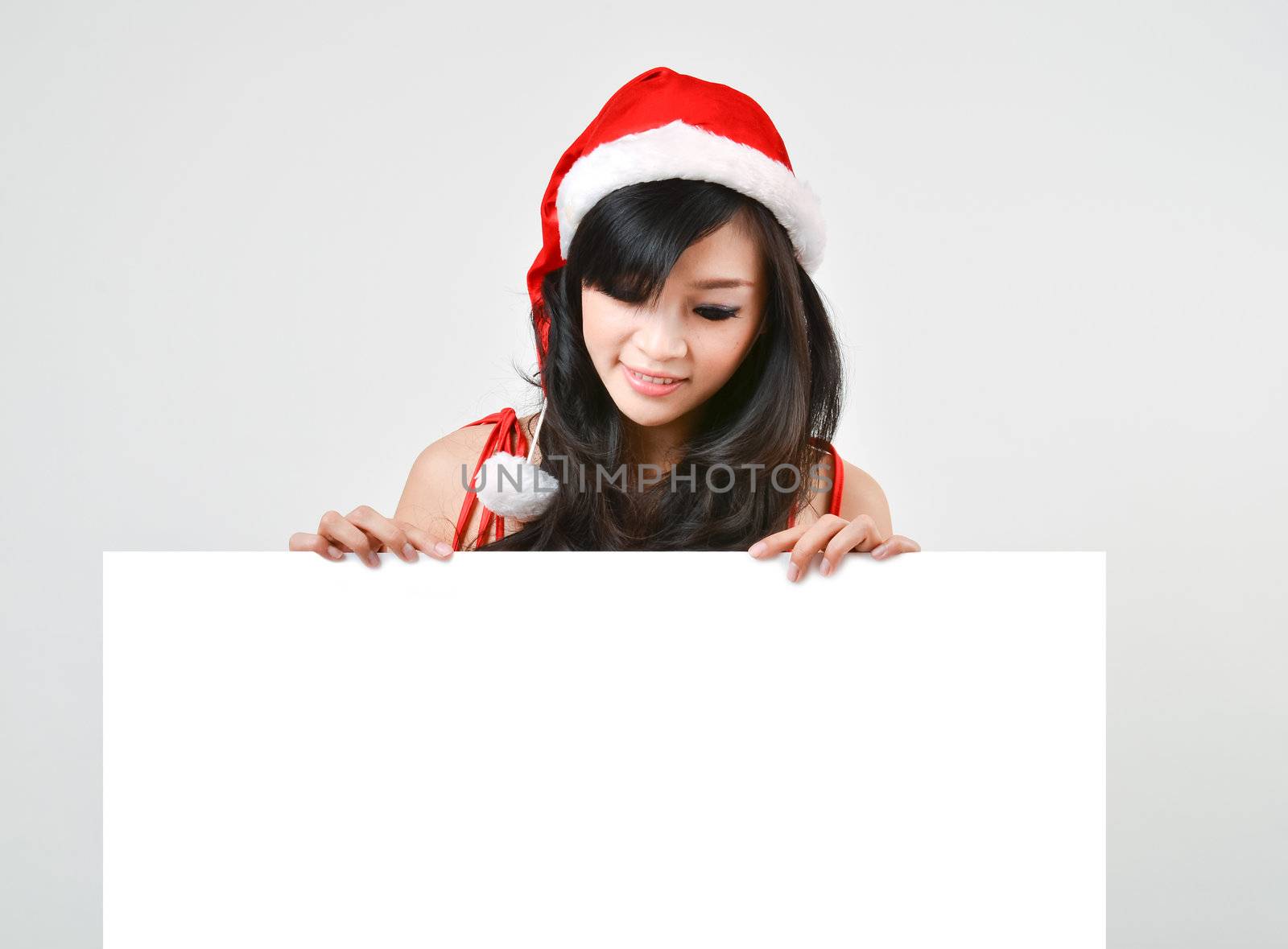 Santa woman  holding a white poster isolated a on gray background