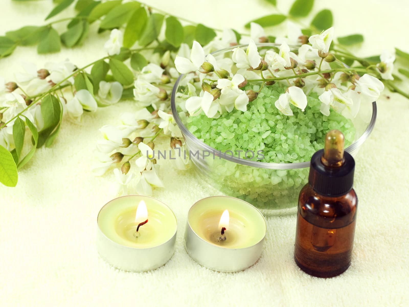 Fragrant flowers, acacia essential oils and candles on a yellow background
