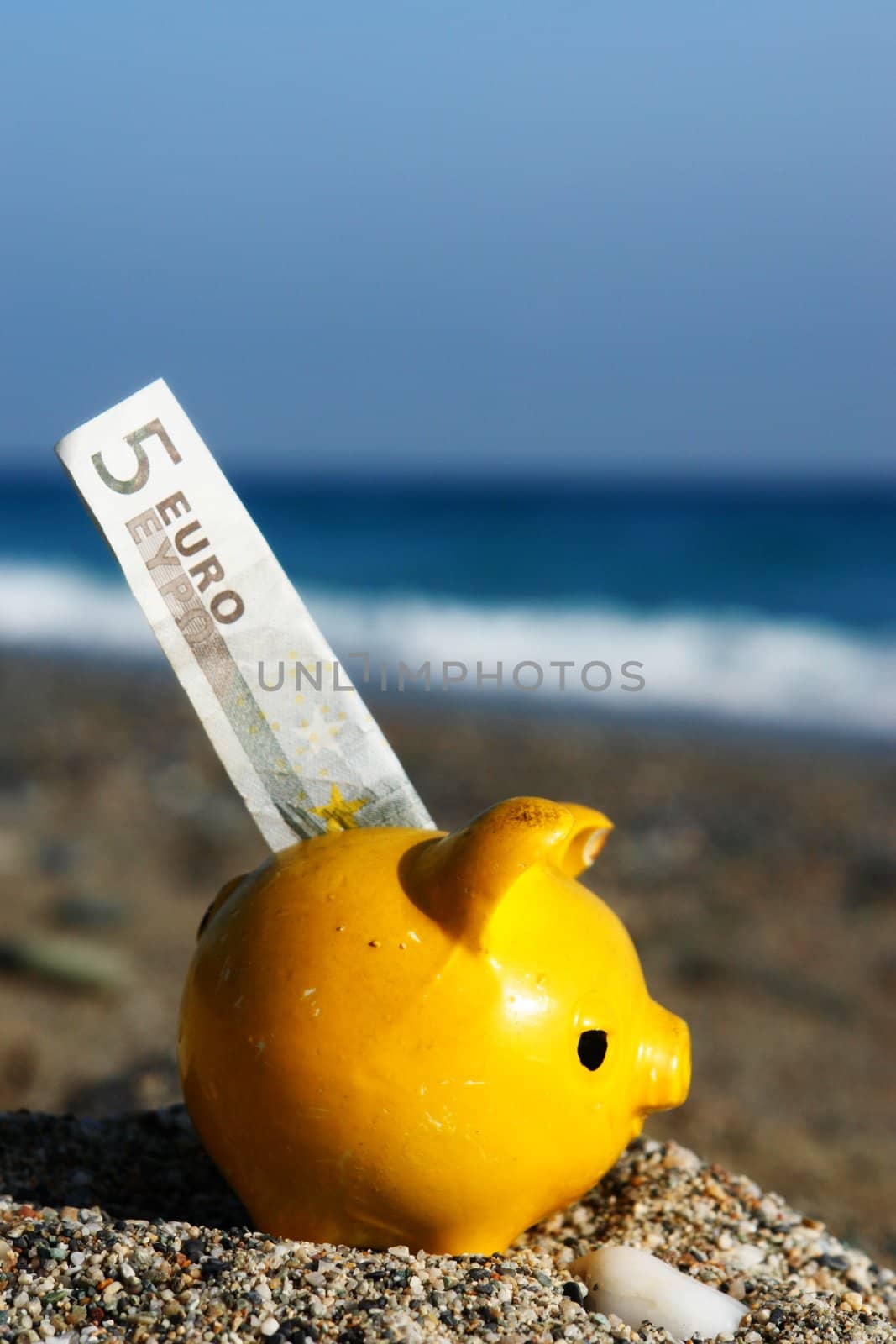 close up of a yellow piggybank on the beach close up of a yellow piggybank on the beach