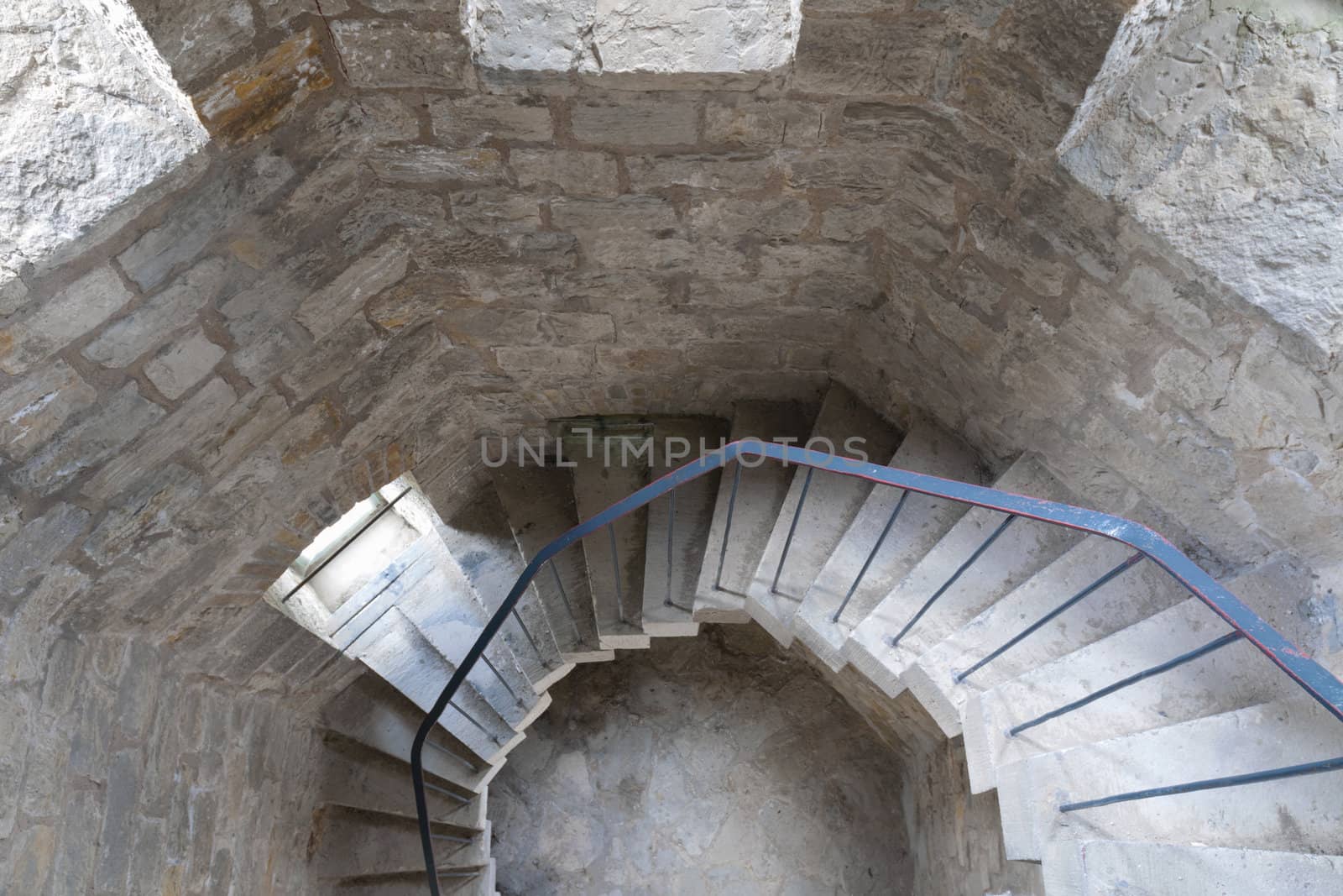concrete spiral stairs with metallic handrails go down