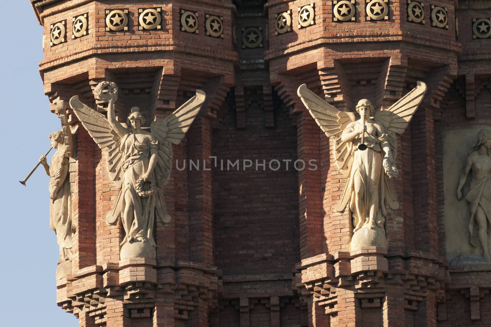 top fragment of famous Arc de Triomf built for the 1888 Universal exhibition in Barcelona, Spain; Figures of angels blowing a horn