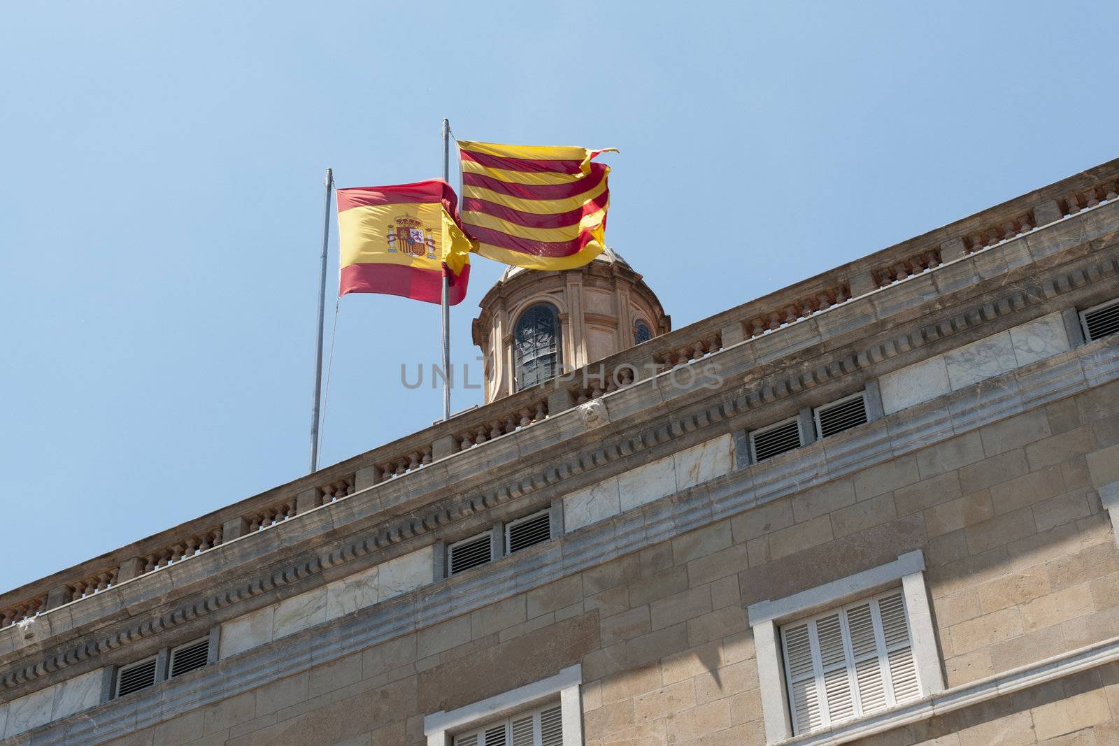 Spain and Catalonia flags on the top of Catalonia government building in Barcelona