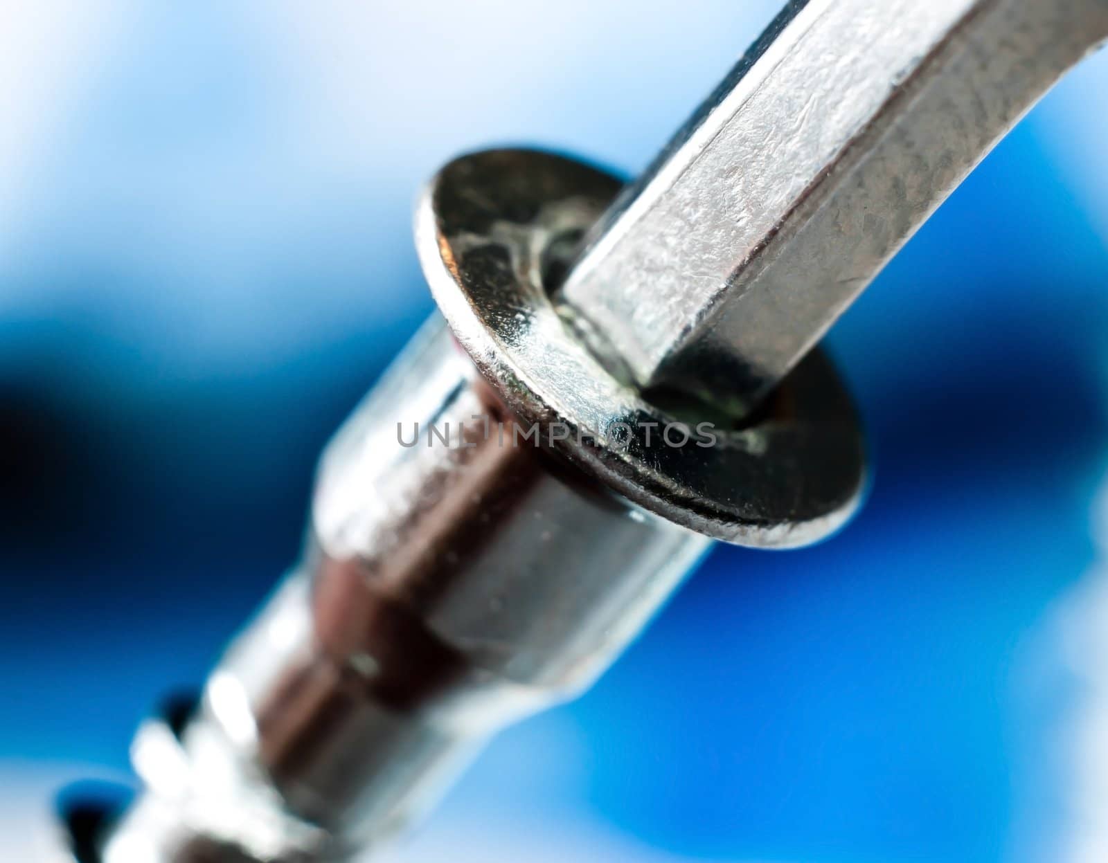 A chrome cap head or allen screw with a wrench, macro