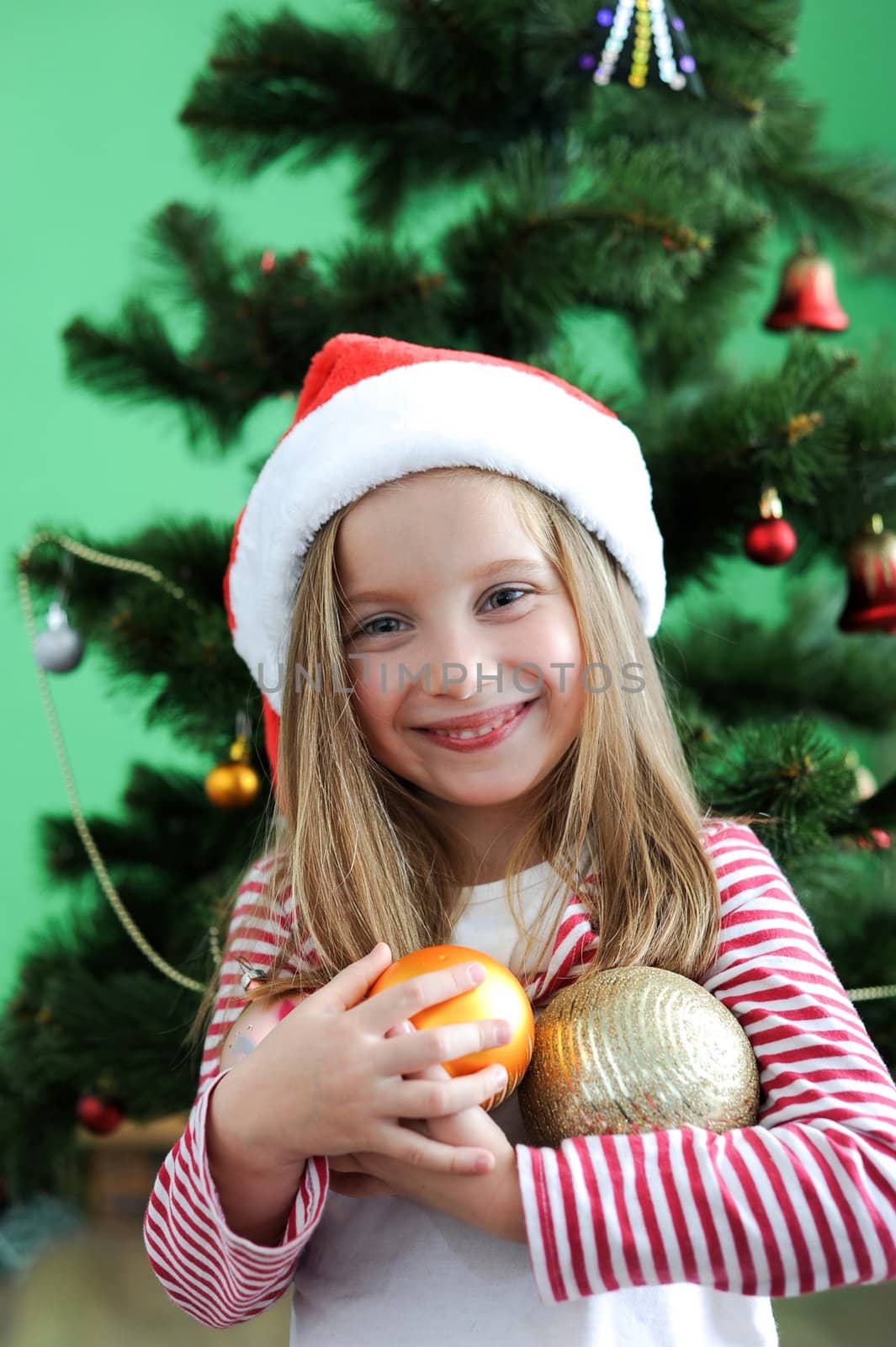 Cute smiling girl in Santa hat with Christmas decoration