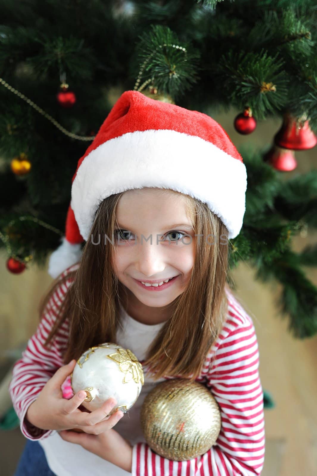 Smiling adorable girl in Santa hat with Christmas decoration