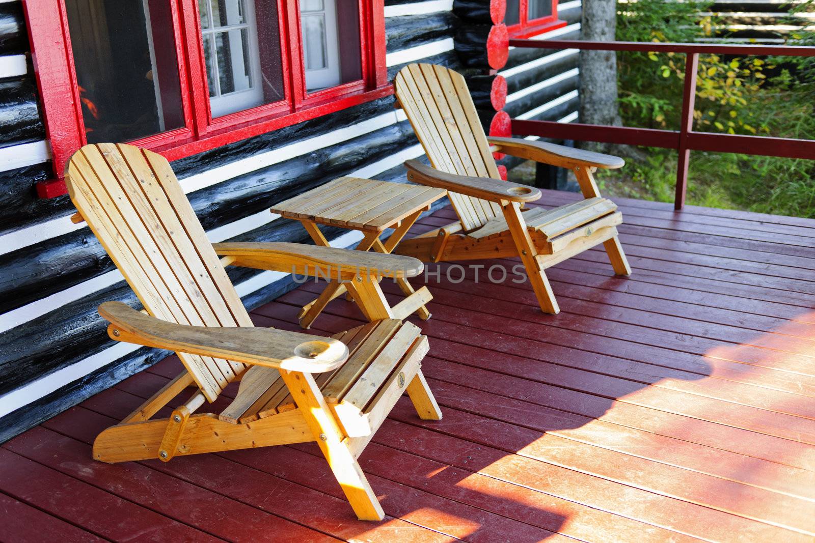 Wooden log cabin cottage porch with adirondack chairs