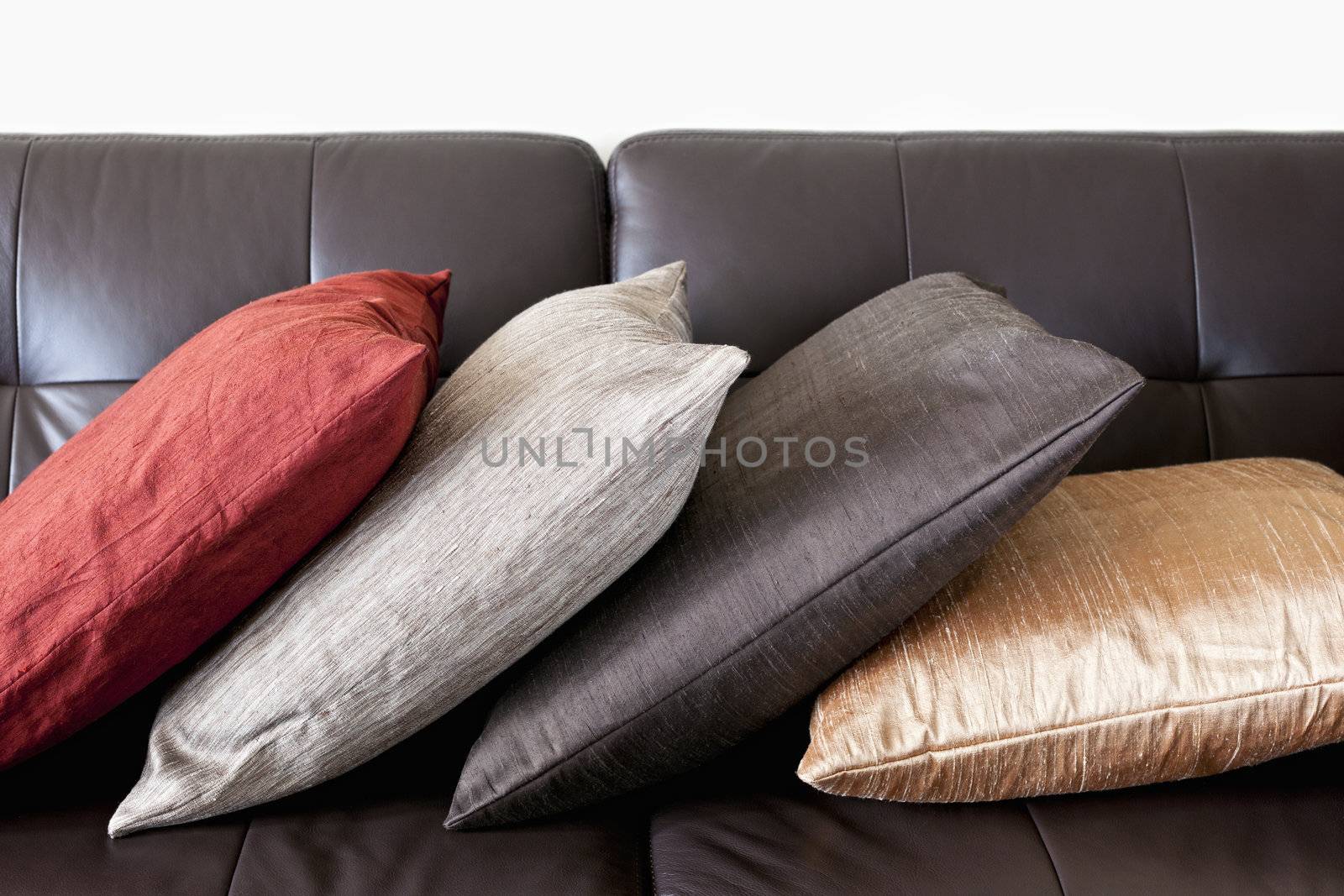 Four colorful cushions on dark brown leather couch