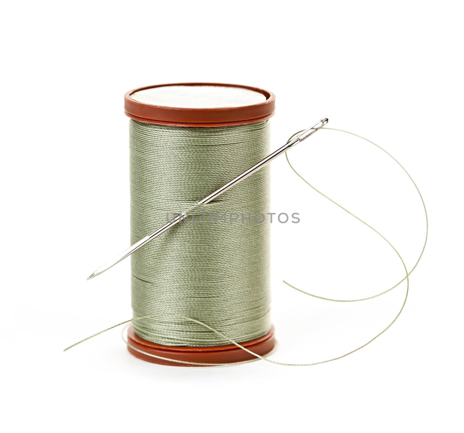 Spool of thread with needle for sewing on white background