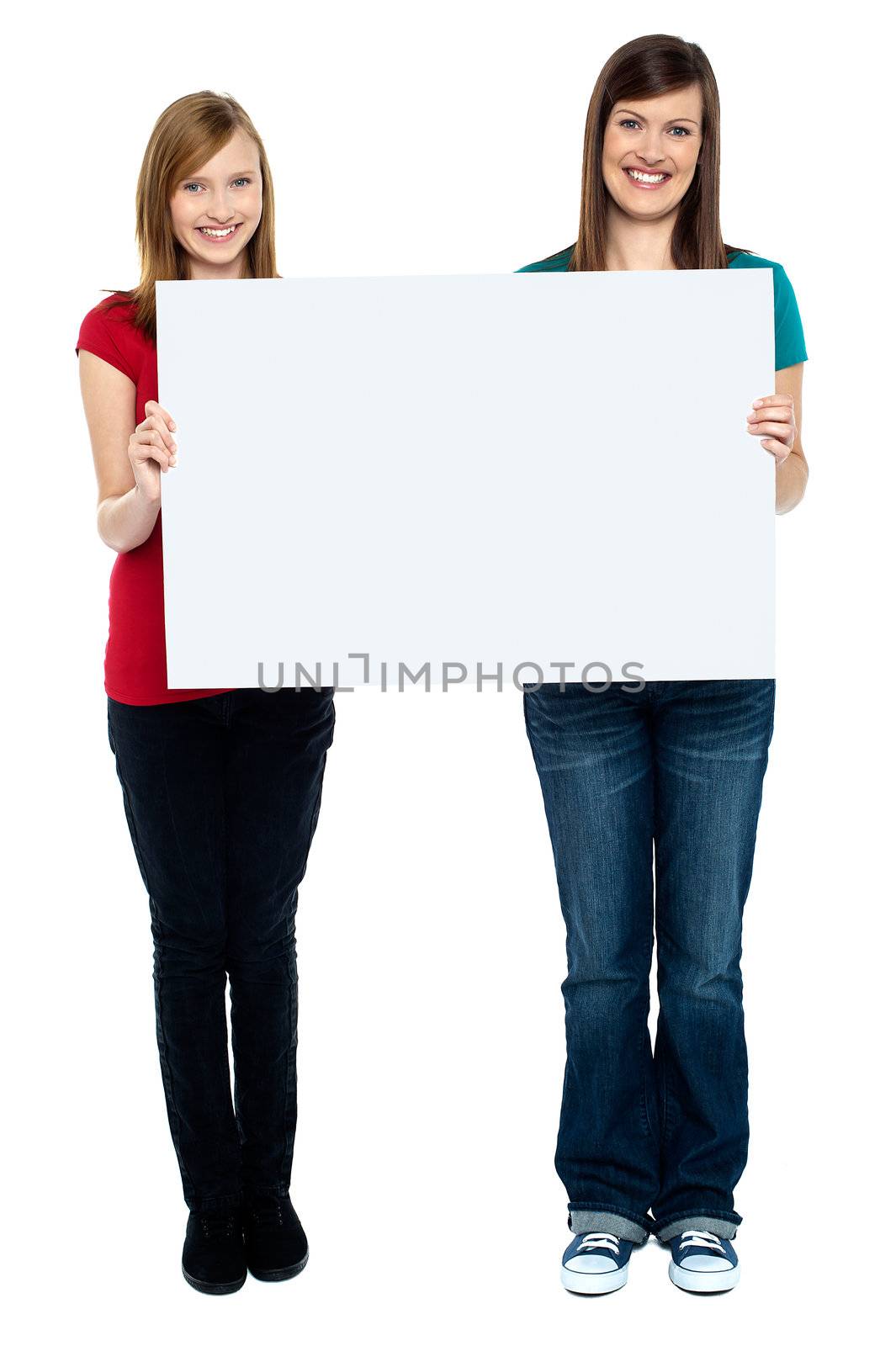 Pair of good looking women holding whiteboard. Full length portrait.