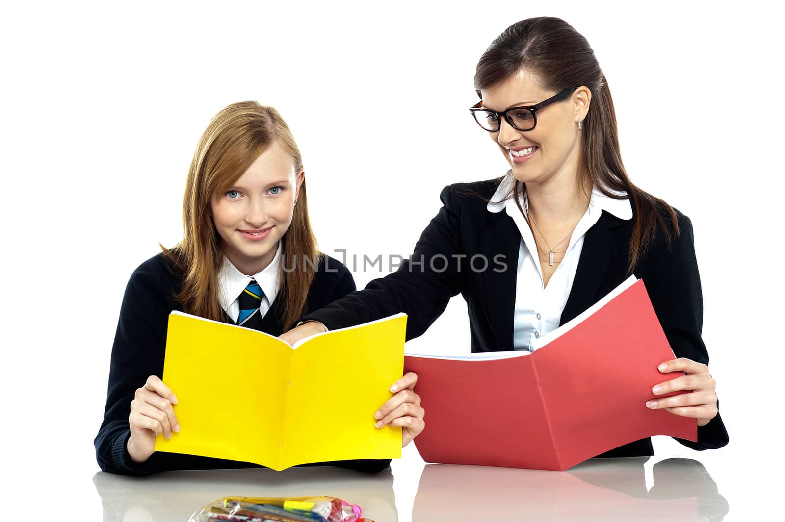 Cheerful educator sitting with a student and taking her through a lesson. Teacher student relationship.