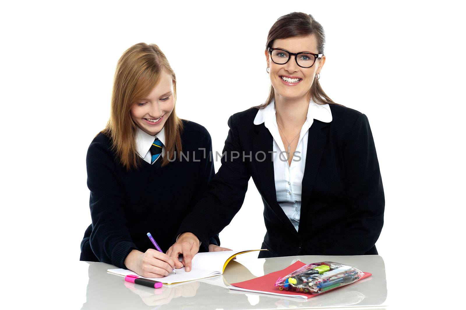 Bespectacled teacher pointing out the mistakes in her students notebook and facing the camera.