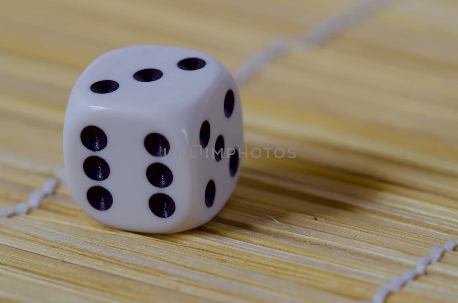 white six sided gaming die with black numbers on a wooden floor