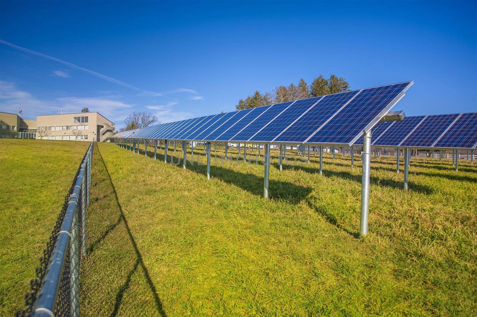 Solar panels in field with blue sky used to furnish electricity to building