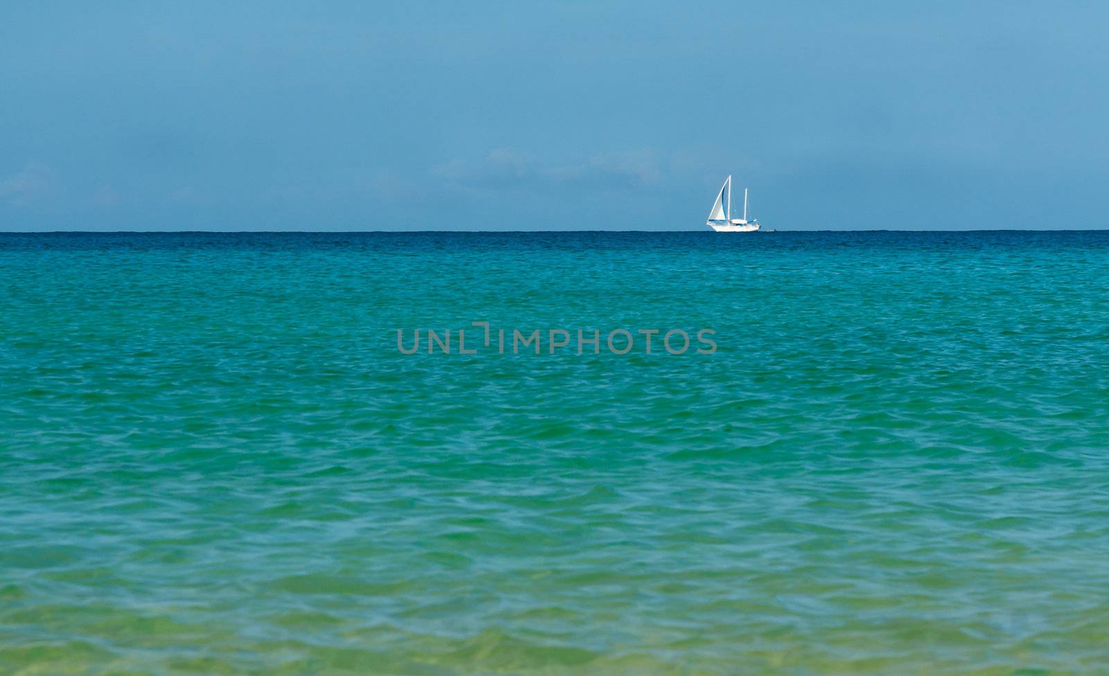 white sailboat on the azure sea on the horizon