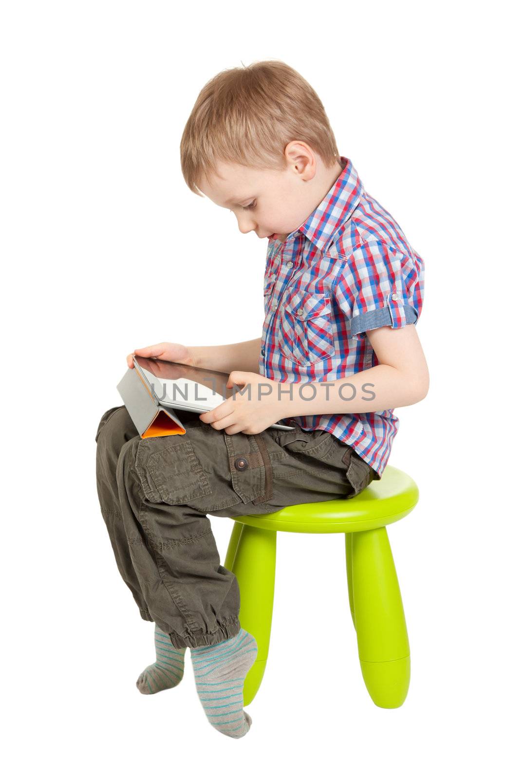boy with a Tablet PC sitting on a chair in the children's green studio isolated on white background