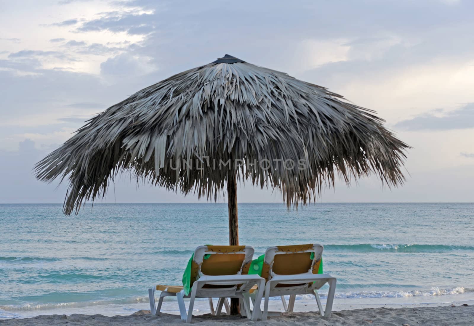 Two chairs facing a cloudy ocean sunset