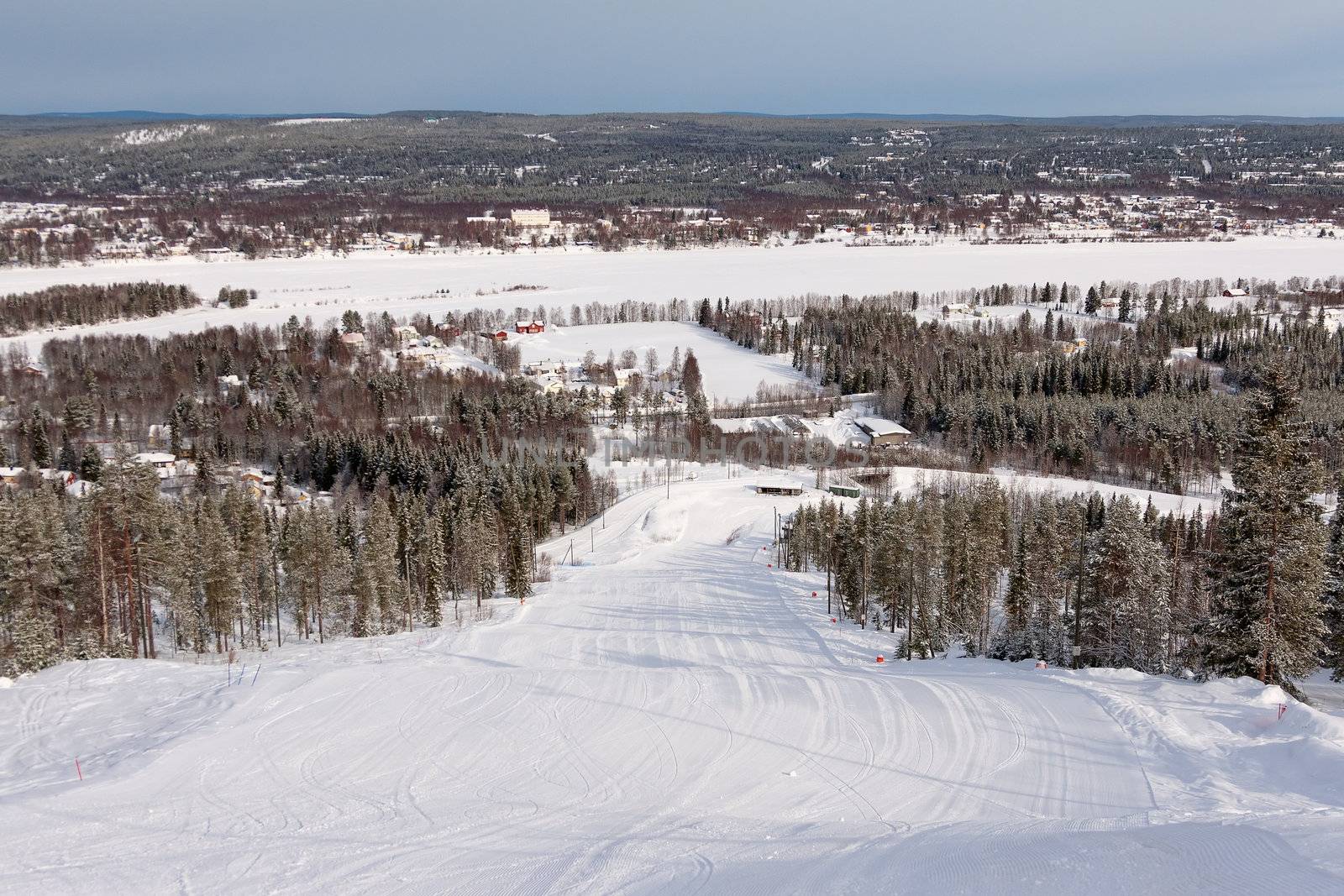 View on empty fresh-made downhill ski slope and mountains on a sunny day