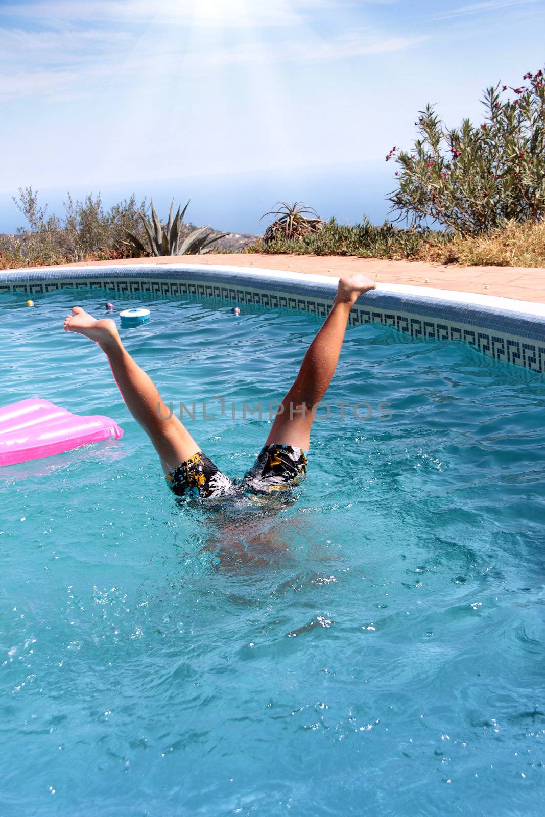 little boy's handstand under the blue pool water