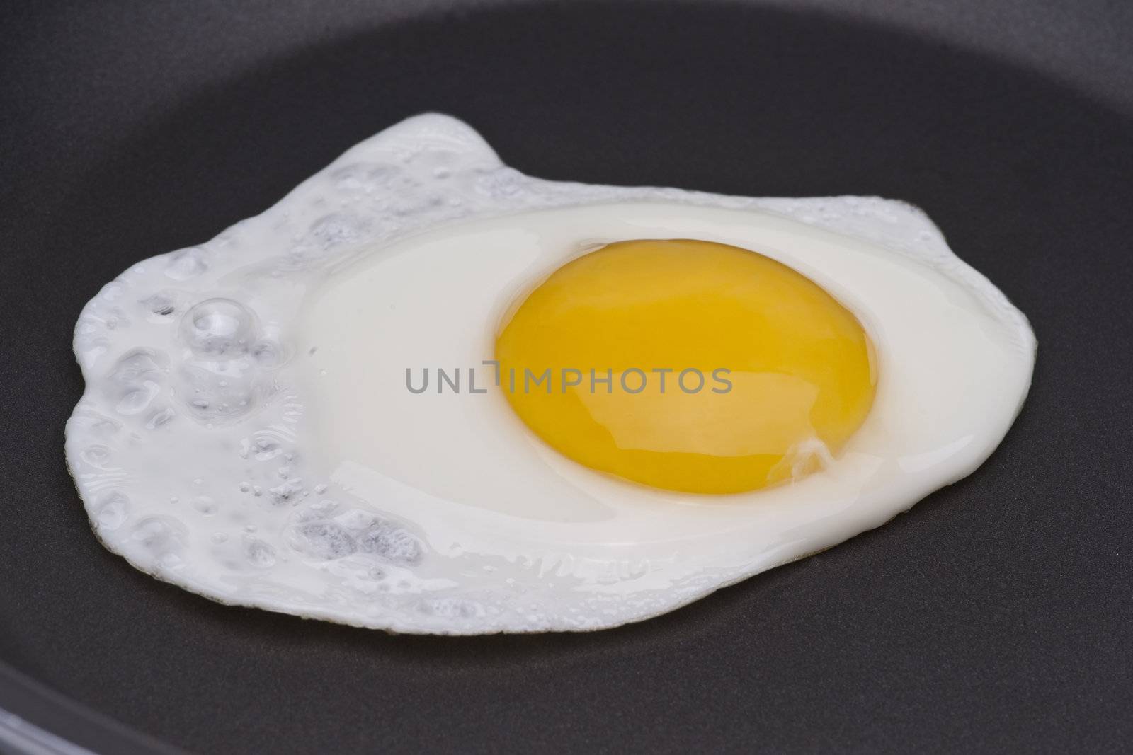 One egg in a black skillet frying pan