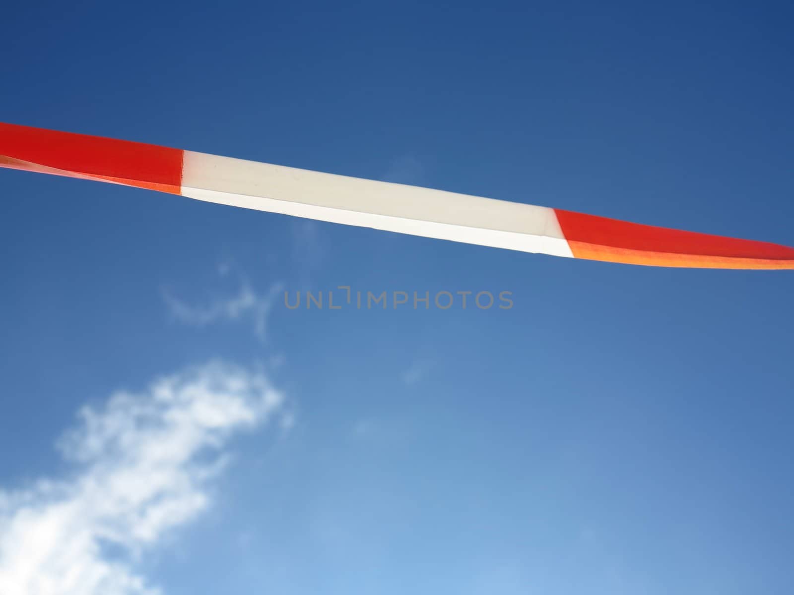 Set of red and white glossy barrier tapes against the sky