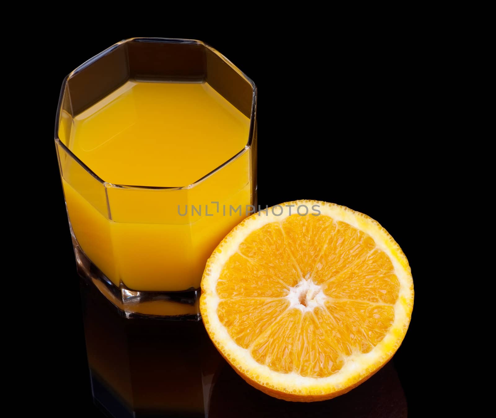 glass of orange juice and half of the orange on black background
