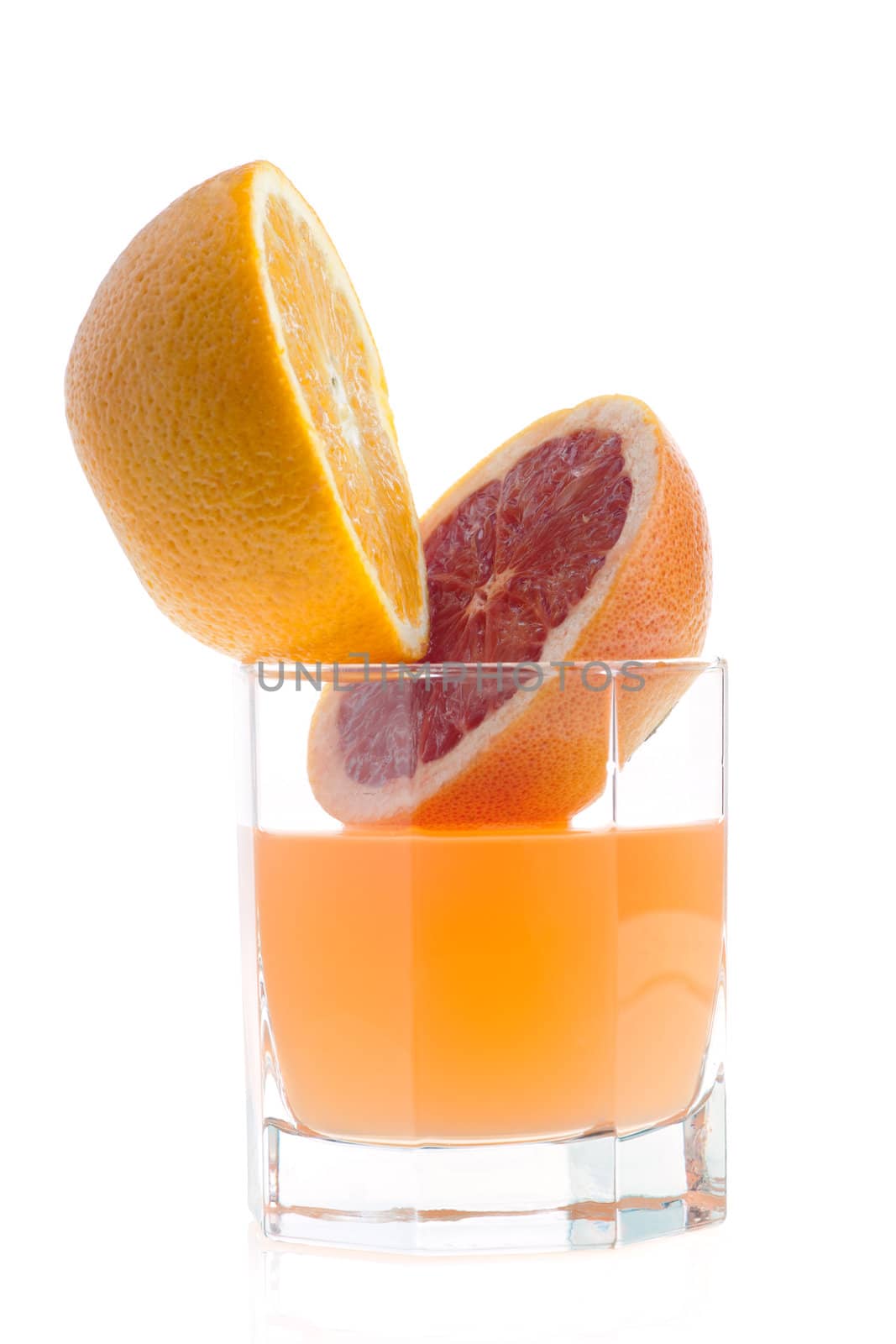 two halves of grapefruit and juice in glass on white
