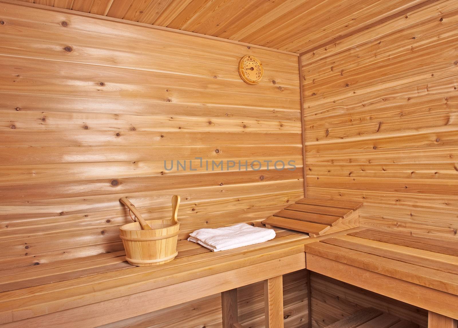 a sauna within a wood cabin with a bucket and towel inside the room