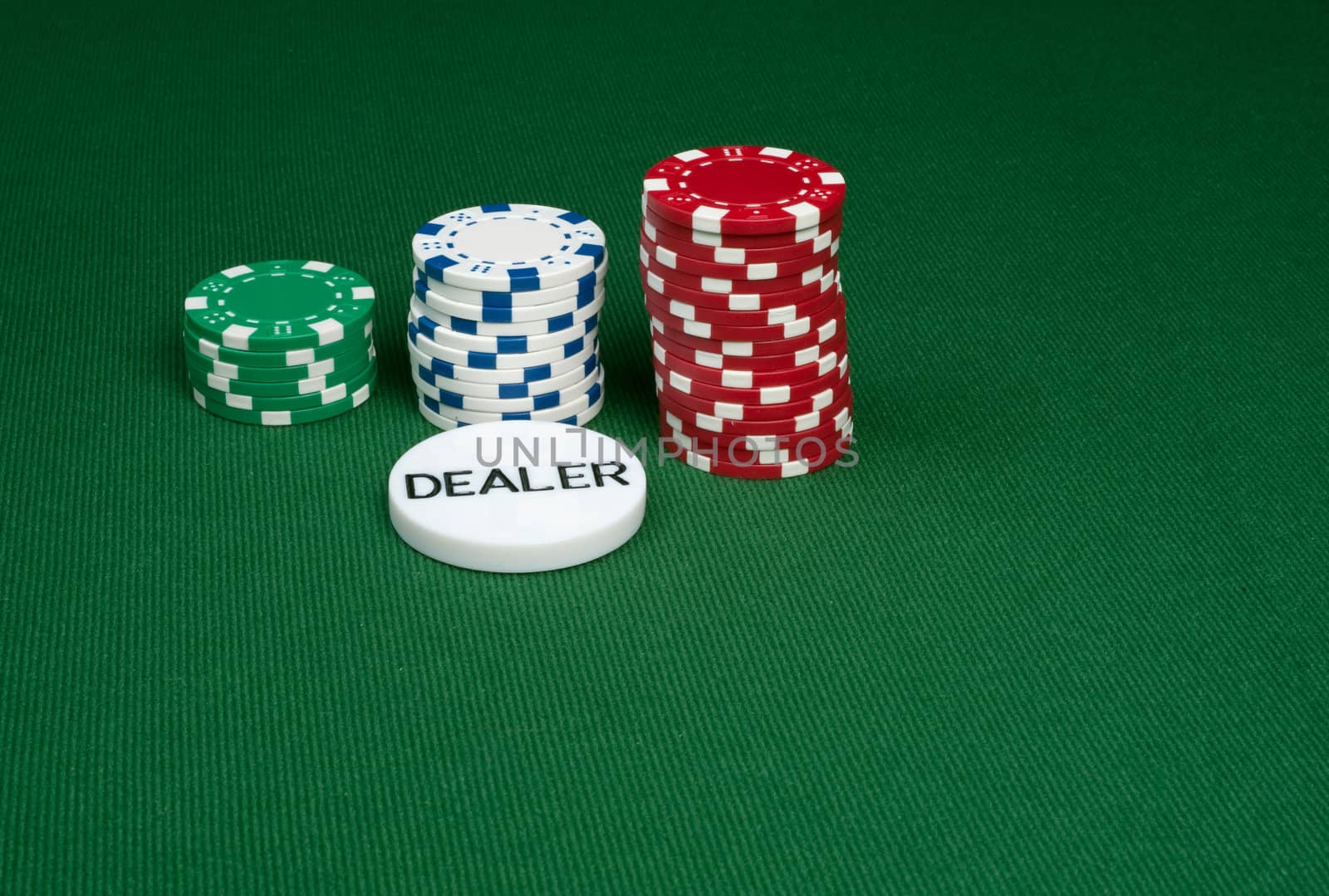 Three stacks of poker chips on a green felt table