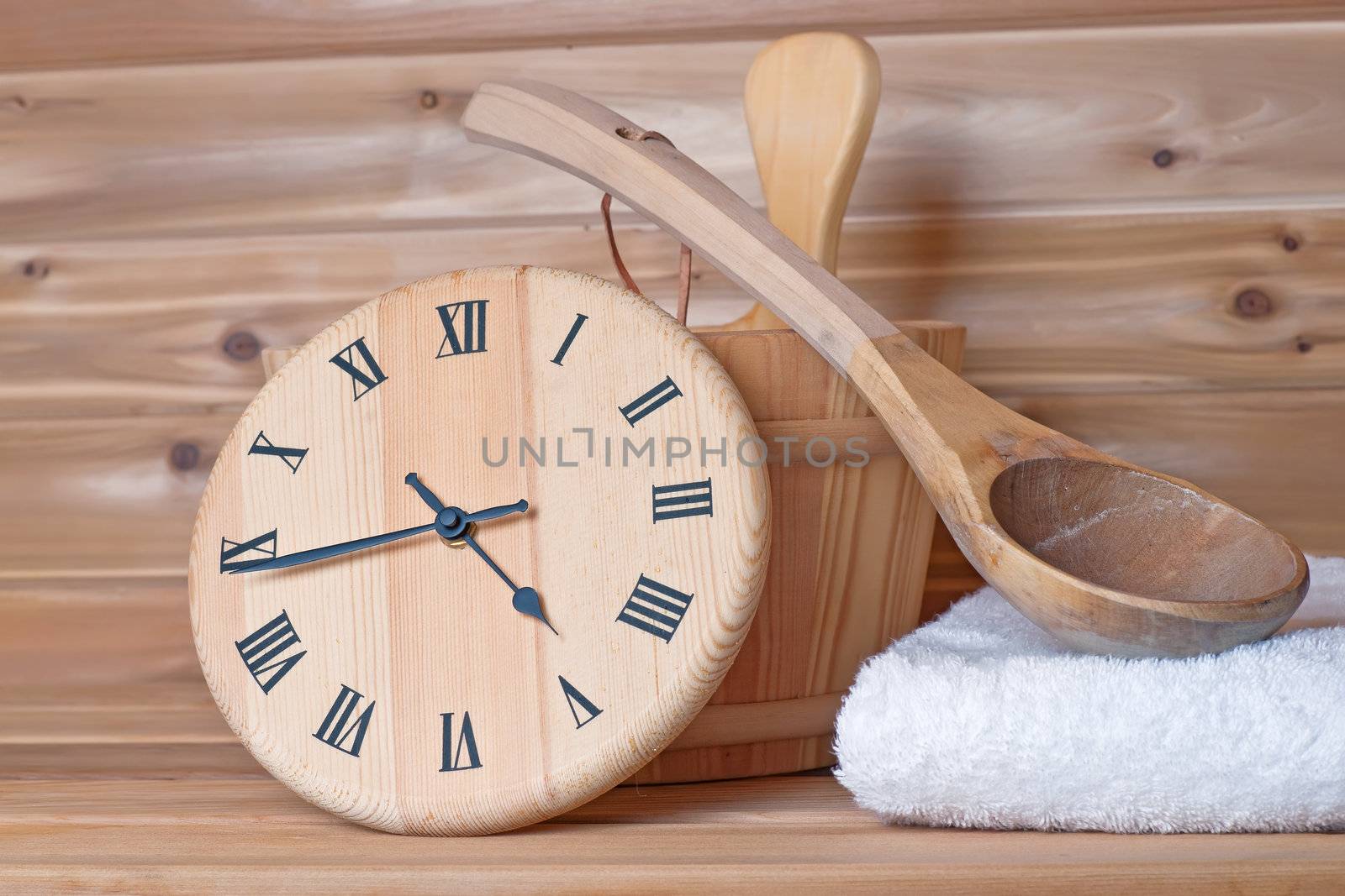 wooden clock that tells time in a wooden sauna with bucket ladle and towel