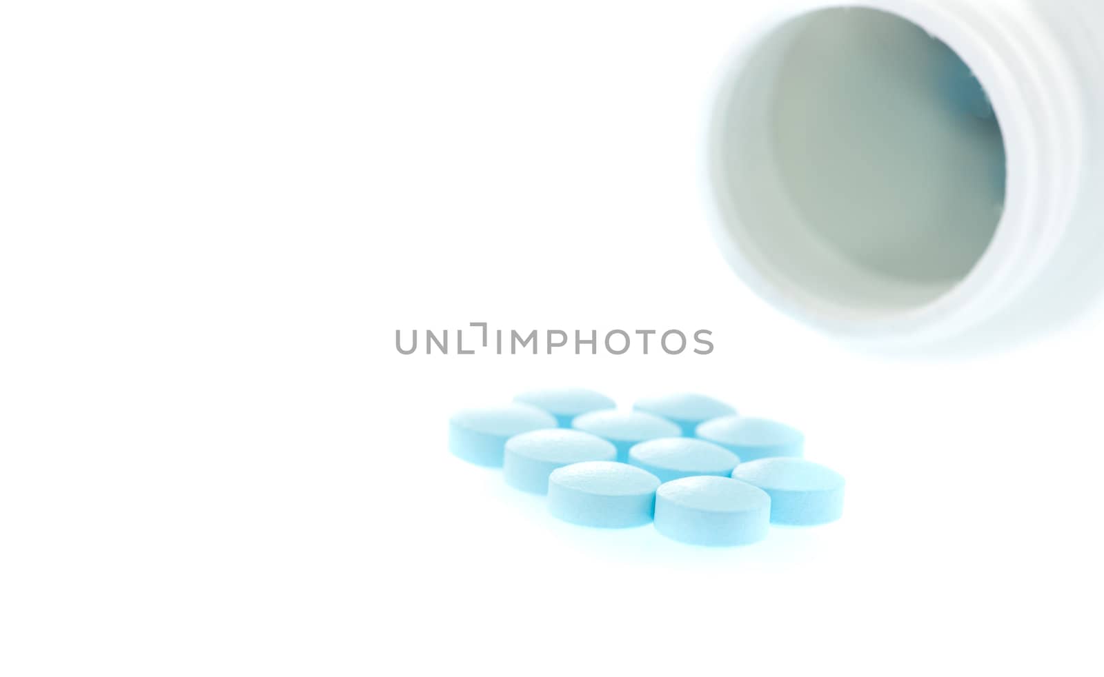 medication spilling from an open bottle. This macro shot shows caplets or pills in the opening of a medicine bottle 
