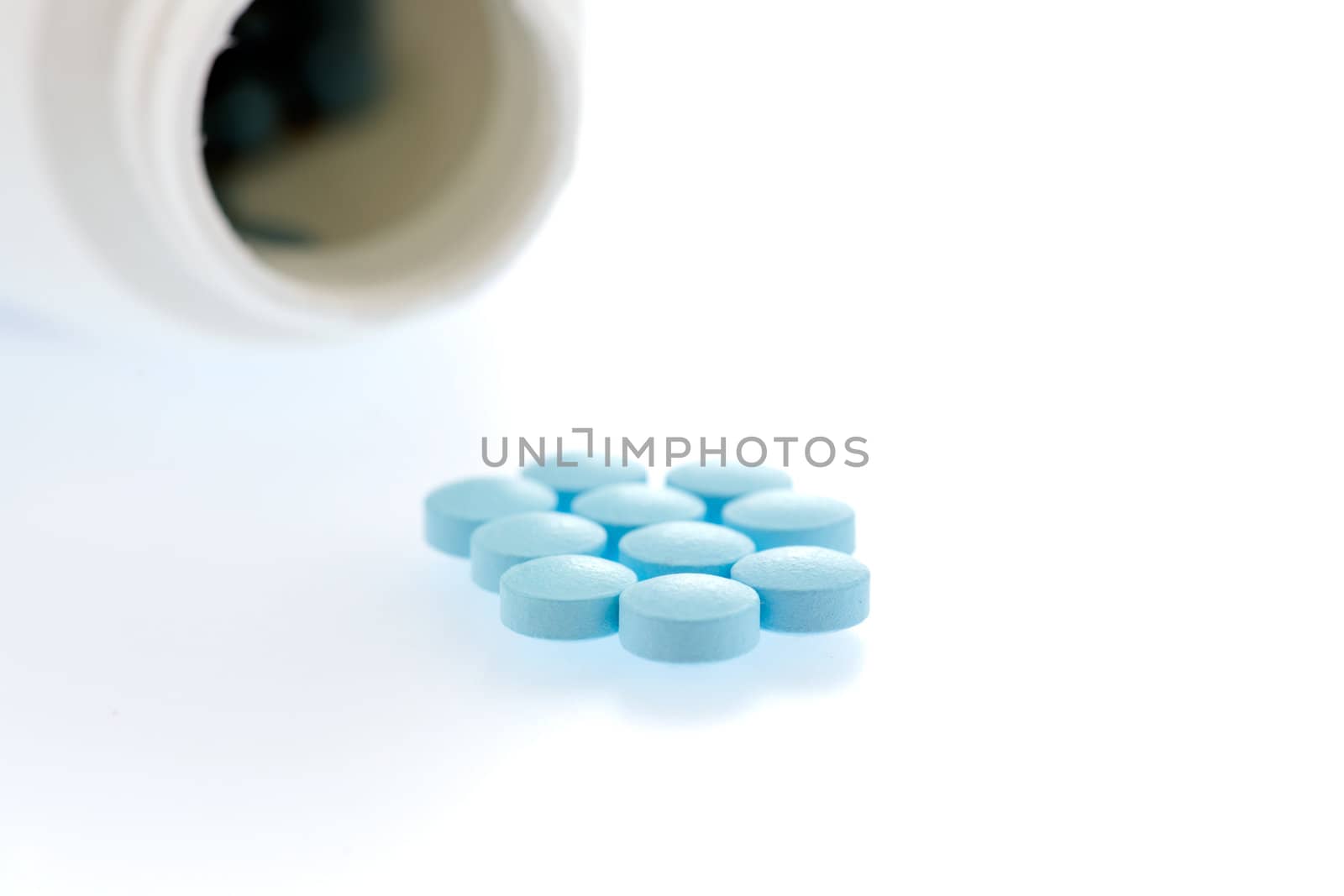 medication spilling from an open bottle. This macro shot shows caplets or pills in the opening of a medicine bottle 