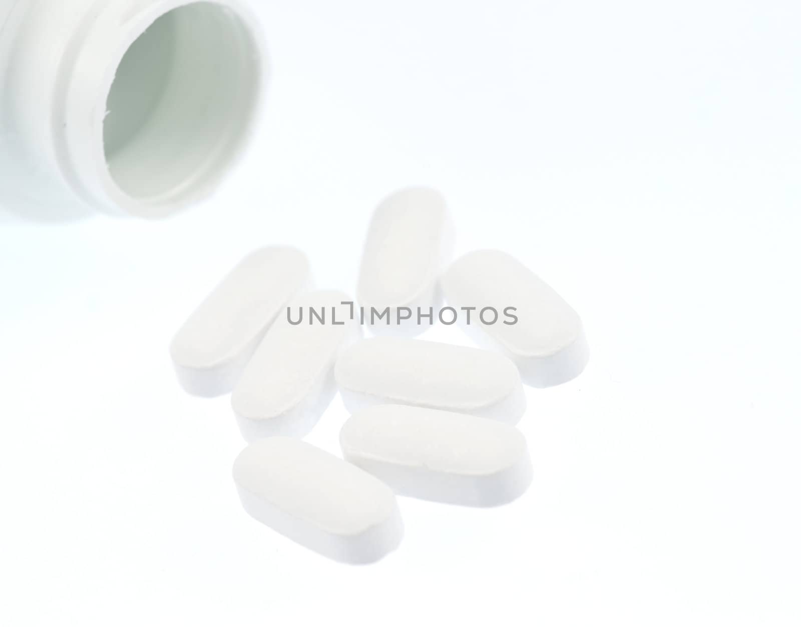 medication spilling from an open bottle. This macro shot shows caplets or pills in the opening of a medicine bottle 