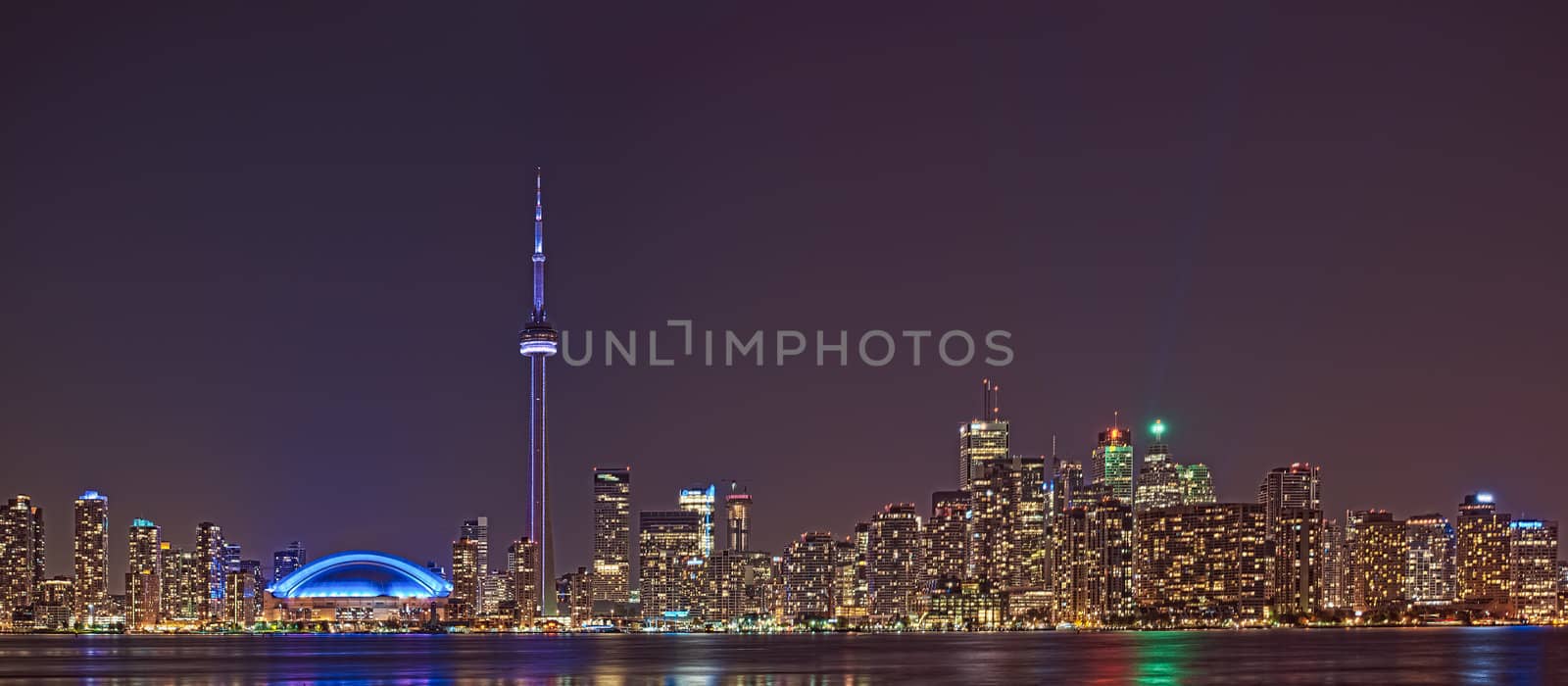 The landmark Toronto downtown view from the center island. Scenic view of the CN Tower illuminated by the iconic downtown skyline of skyscrapers and high rise condominiums reflecting in Lake Ontario 