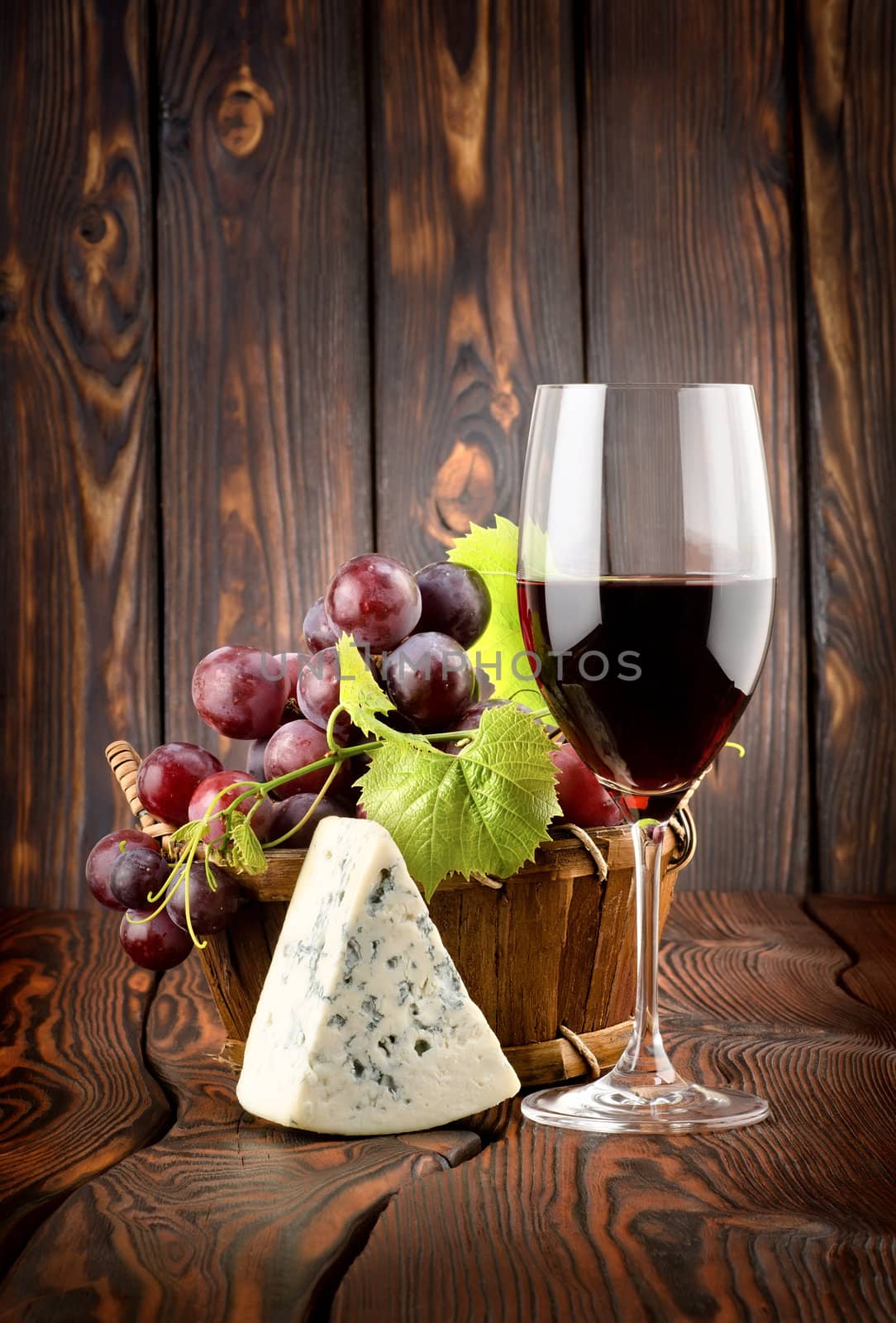 Wine glass and grapes in a basket on a wooden background