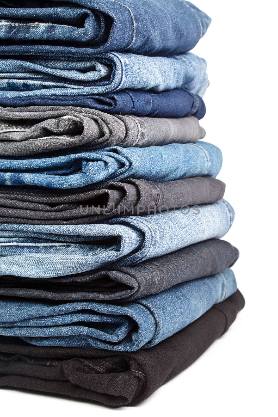 Stack of blue and black Jeans on white background