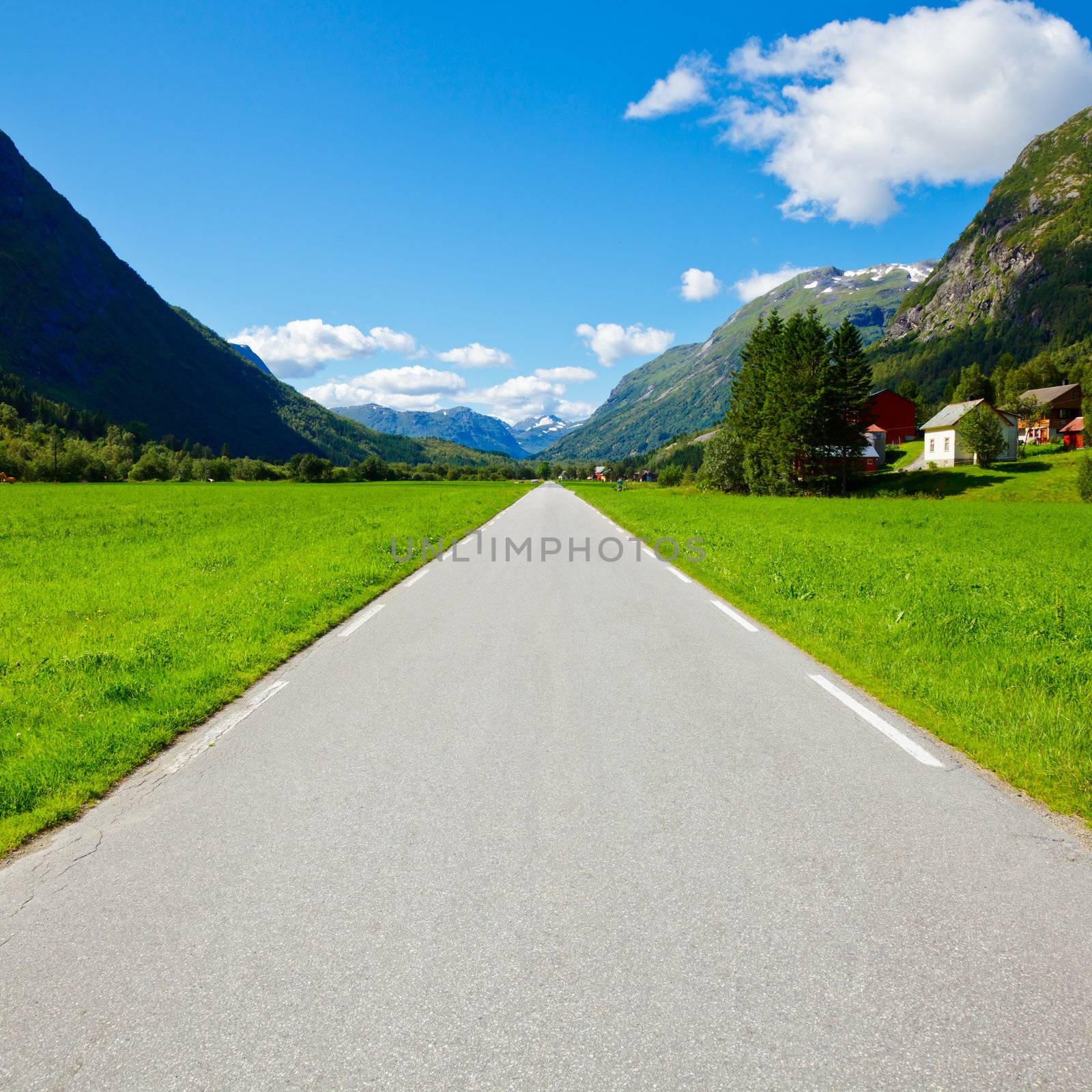 Scenic one lane asphalt road leads through mountain valley in Norway